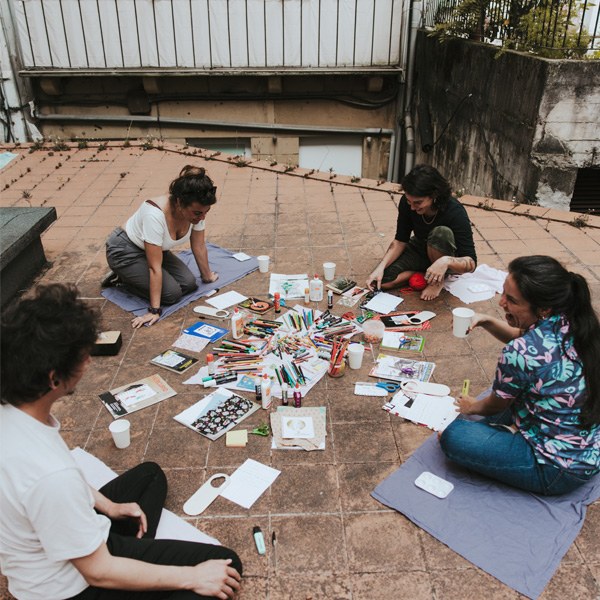Grupo de personas trabajando con papel y materiales artísticos en el suelo